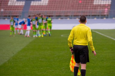 Futbol hakemi, arka planda futbol maçı.