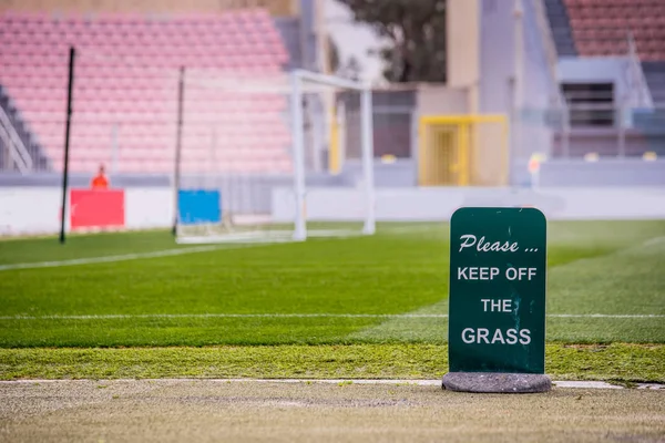 "Please Keep of the Grass "- tittle on green board at soccer stadium. Футбольная сетка — стоковое фото