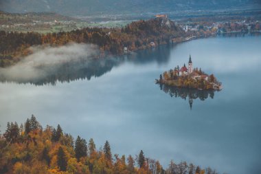Bled, Slovenya - Ojstrica perspektifinden Bled Gölü 'nün panoramik ufuk çizgisi manzarası Maria' nın Hacı Kilisesi, geleneksel Pletna tekneleri ve arka planda Bled Castle ile sonbaharda çekildi