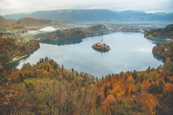 Luftaufnahme der Kirche Mariä Himmelfahrt auf dem Bleder See. Sonnige Herbstlandschaft in den Julischen Alpen, Slowenien, Europa. — Stockfoto