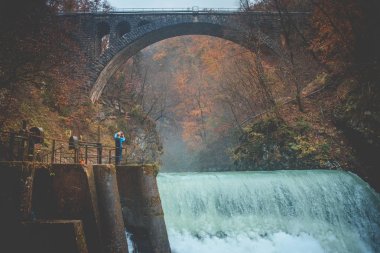 Turistler Vintga 'daki vahşi nehrin üzerindeki eski köprünün fotoğrafını çeker.