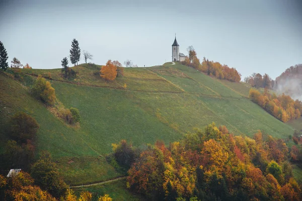 Malý kostel na vrcholu kopce v podzimní deštivé přírodě. Jamnik, Slovinsko. — Stock fotografie