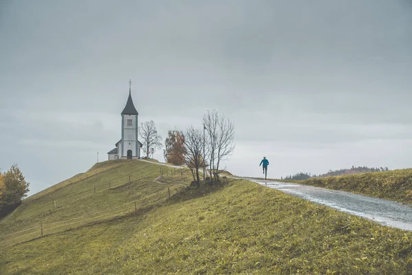 Trilha correr no topo da colina em belo ambiente. Igreja romântica pequena no fundo — Fotografia de Stock