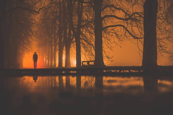 Człowiek spacerujący w ciemnej alejce w nocy — Zdjęcie stockowe