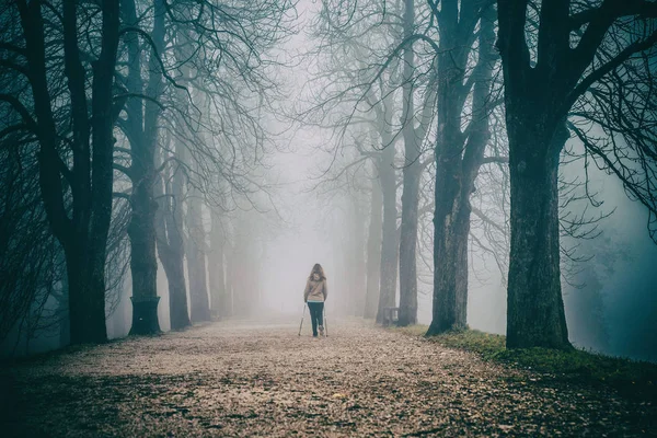 Samotna kobieta i poranny spacer we mglistym parku pełnym drzew — Zdjęcie stockowe