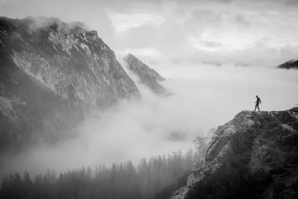 Tourist looking to the valley on misty autumn landscape. Black and white photo. Julian Alps, Slovenia