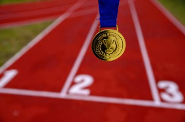 Altın madalya, arka planda kırmızı koşu pisti, spor motivasyon konsepti fotoğrafı. Tokyo 2020 Yaz Olimpiyatları için orijinal fotoğraf