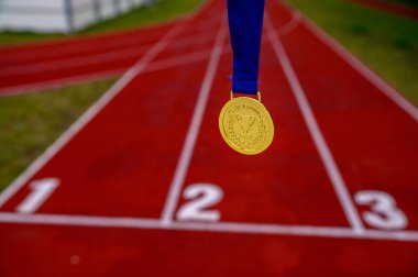 Spor ilhamı, konsept fotoğraf, altın madalya, arka planda kırmızı koşu pisti, spor motivasyon konsepti fotoğrafı. Tokyo 2020 Yaz Olimpiyatları için orijinal fotoğraf