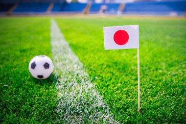 Japonya bayrağı ve futbol topu yeşil çimlerin üzerinde. Hayranlar, fotoğrafı destekleyin, alanı düzenleyin