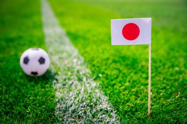 Japonya bayrağı ve futbol topu yeşil çimlerin üzerinde. Hayranlar, fotoğrafı destekleyin, alanı düzenleyin