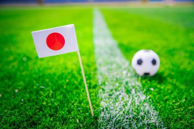 Japonya bayrağı ve futbol topu yeşil çimlerin üzerinde. Hayranlar, fotoğrafı destekleyin, alanı düzenleyin