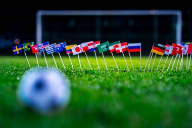 Yeşil çimlerde futbol topu ve Dünya Kupası 'nın tüm ulusal bayrakları