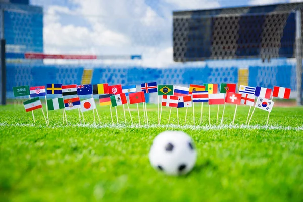 サッカーの緑の芝生の上のすべての国のフラグ 背景にはサッカーネットと青空 — ストック写真