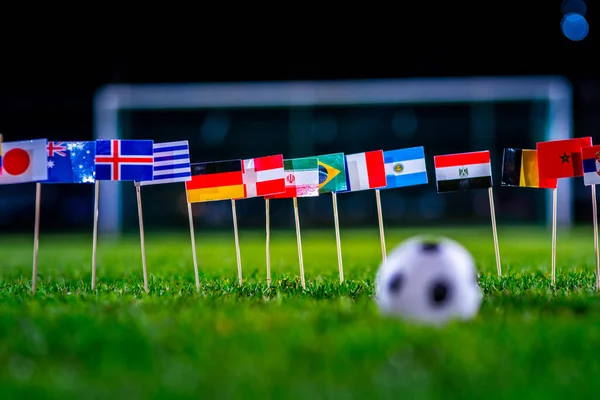 Yeşil çimlerde futbol topu ve Dünya Kupası 'nın tüm ulusal bayrakları