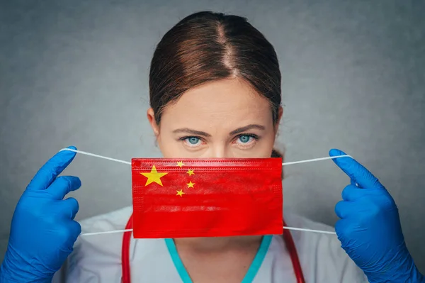 Coronavirus in China Female Doctor Portrait hold protect Face surgical medical mask with China National Flag. Illness, Virus Covid-19 n China, concept photo
