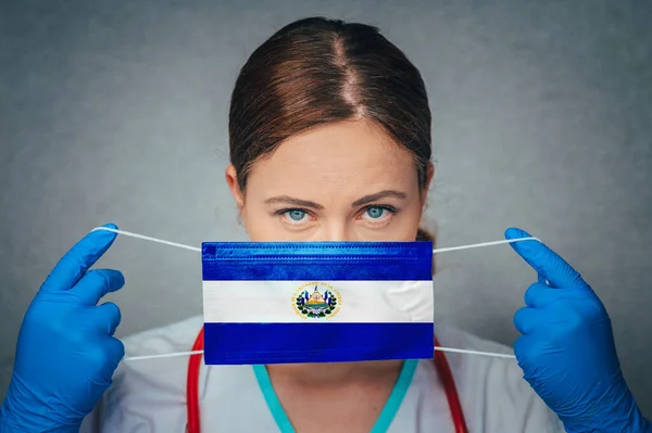 Coronavirus in El Salvador Female Doctor Portrait hold protect Face surgical medical mask with El Salvador National Flag. Illness, Virus Covid-19 in El Salvador, concept photo