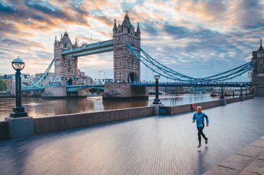 Coronavirus, Covid-19 karantina zamanında Londra 'nın boş sokaklarında tek başına koşuyor. Kule Köprüsü arkaplanda