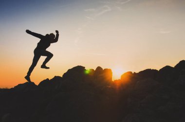 Sakin yaz günbatımında tepenin tepesinde koşan koşucunun silueti. Dağlarda koşan iz, fotokopi alanı olan konsept fotoğraf.