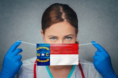 Coronavirus in U.S. State North Carolina, Female Doctor Portrait, protect Face surgical medical mask with North Carolina Flag. Illness, Virus Covid-19 in North Carolina clipart