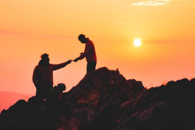 İki arkadaş birbirine yardım ediyor ve takım çalışması ile harika yaz gündoğumunda dağların zirvesine ulaşmaya çalışıyorlar..