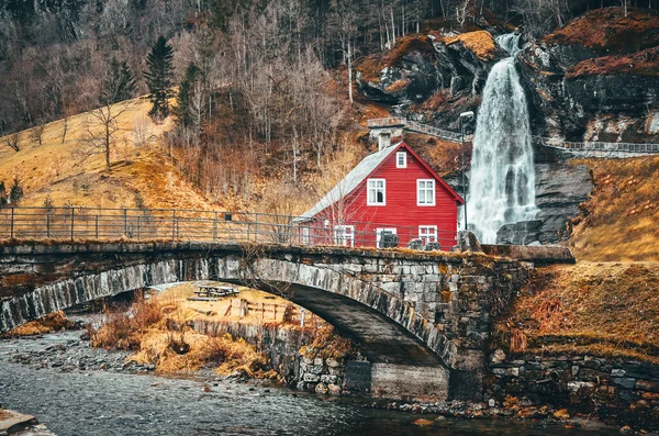 Waterfall and typical red house in Norway National park Tvindefossen