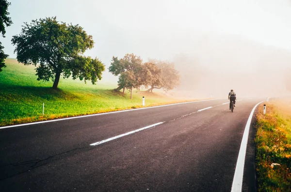 Człowiek Rowerze Jeździć Przez Mglisty Krajobraz Pobliżu Dużego Drzewa Zdjęcie — Zdjęcie stockowe