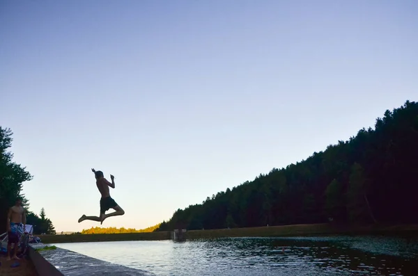 Man jumping to the water in summer in summer evening