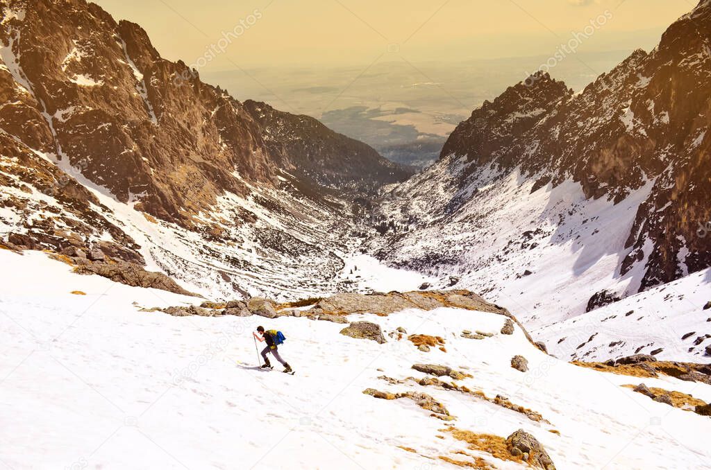 Skier walking up hill in mountains with beautiful wide valley in background