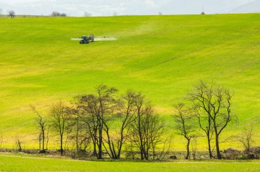 İlkbahar tarım alanını hazırlayan traktör ve toprağa yardımcı olan böcek ilacı kullanıyor.