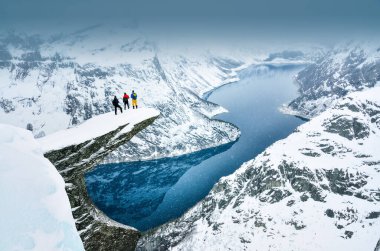 Norveç 'teki ünlü Trolltunga kayasının üzerinde duran ve dağlara bakan ağaç çocukları.