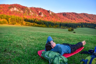 Turistler dinleniyor sonbahar akşamı çayırlarında, arka planda renkli ağaçlar