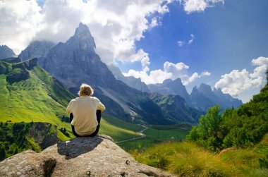 Passo Rolle, İtalya 'da kayanın üzerinde dinlenen bir adam var. Yaz tatilinden sahne.