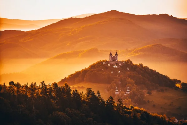 Romantik sabah manzarası. Tepenin tepesinde iki kulesi olan bir kilise. Güzel, ılık yaz sabahı ışığında. Fotokopi çekilen peri kuyruğu fotoğrafı. Banska Stiavnica, Slovakya, Unesco