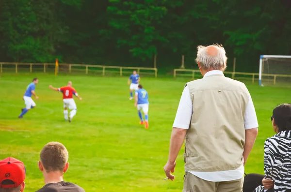 Fan standing and looking at local football match