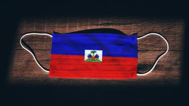Haiti Ulusal Bayrağı tıbbi, cerrahi, siyah ahşap arka planda koruma maskesi. Coronavirus Covid19, enfeksiyonu, hastalığı ya da gribi önleyin. OHAL, tecrit.