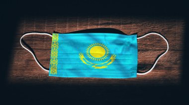 Kazakistan Ulusal Bayrağı tıbbi, cerrahi, siyah ahşap arka planda koruma maskesi. Coronavirus Covid19, enfeksiyonu, hastalığı ya da gribi önleyin. OHAL, tecrit.