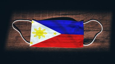 Filipinler Ulusal Bayrağı tıbbi, cerrahi, siyah ahşap arka planda koruma maskesi. Coronavirus Covid19, enfeksiyonu, hastalığı ya da gribi önleyin. OHAL, tecrit.