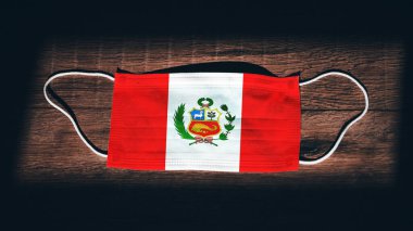 Peru Ulusal Bayrağı tıbbi, cerrahi, siyah ahşap arka planda koruma maskesi. Coronavirus Covid19, enfeksiyonu, hastalığı ya da gribi önleyin. OHAL, tecrit.