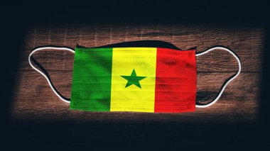 Senegal Ulusal Bayrağı tıbbi, cerrahi, siyah ahşap arka planda koruma maskesi. Coronavirus Covid19, enfeksiyonu, hastalığı ya da gribi önleyin. OHAL, tecrit.