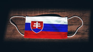Slovakya Ulusal Bayrağı tıbbi, cerrahi, siyah ahşap arka planda koruma maskesi. Coronavirus Covid19, enfeksiyonu, hastalığı ya da gribi önleyin. OHAL, tecrit.