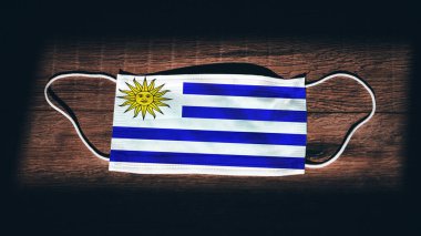 Uruguay Ulusal Bayrağı tıbbi, cerrahi, siyah ahşap arka planda koruma maskesi. Coronavirus Covid19, enfeksiyonu, hastalığı ya da gribi önleyin. OHAL, tecrit