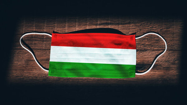 Государственный флаг Венгрии на медицинском, хирургическом, защитном фоне на черном деревянном фоне. Коронавирус Covid19, инфекция Prevent, болезнь или грипп. Чрезвычайное положение, изоляция
.