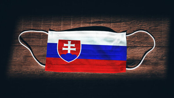 Государственный флаг Словакии на медицинском, хирургическом, защитном фоне на черном деревянном фоне. Коронавирус Covid19, инфекция Prevent, болезнь или грипп. Чрезвычайное положение, изоляция
.