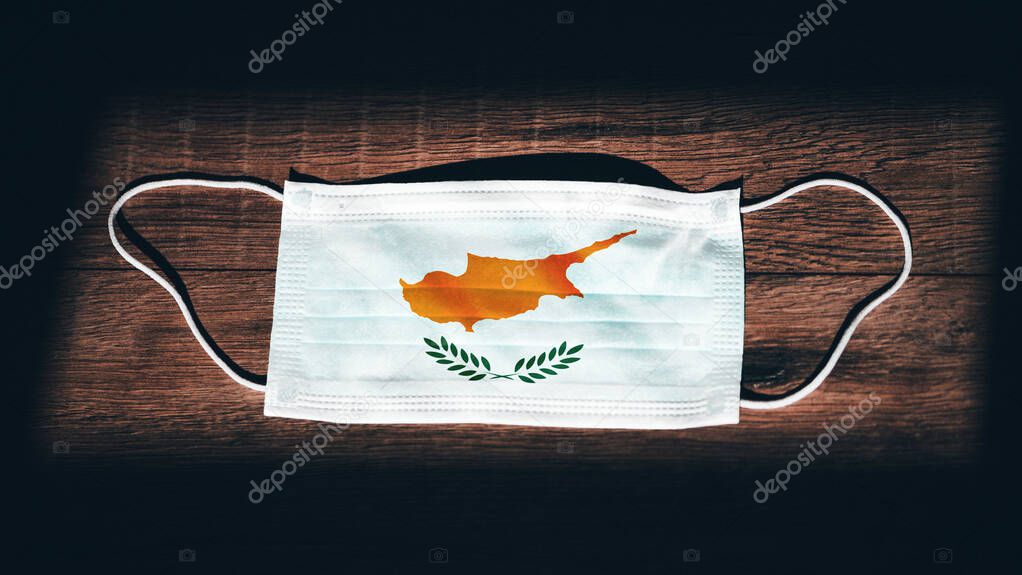 Cyprus National Flag at medical, surgical, protection mask on black wooden background. Coronavirus Covid19, Prevent infection, illness or flu. State of Emergency, Lockdown.