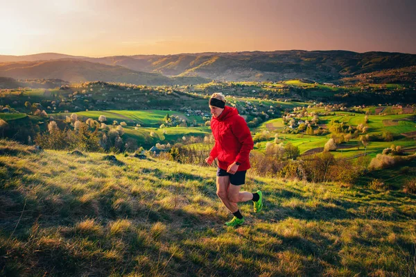 Male runner training in spring morning nature. Man running up hill. Beautiful spring scenery in background. Hrinova village in Slovakia