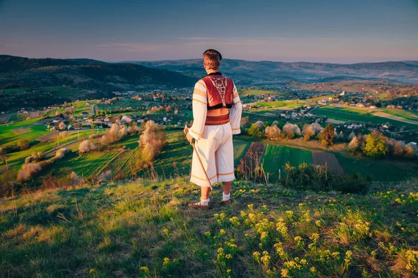 一位身着斯洛伐克民族服装的年轻人正在观看斯洛伐克Hrinova村的春天风景 升起的太阳和背景中盛开的春天的树木 编辑空间 — 图库照片