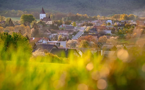 春の日没の光の丘の下の小さな村 — ストック写真