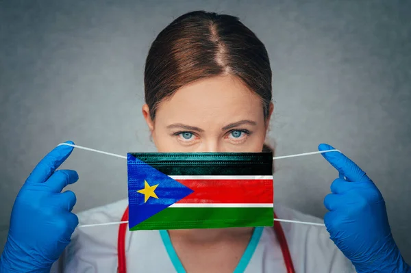 Coronavirus in South Sudan Female Doctor Portrait hold protect Face surgical medical mask with South Sudan National Flag. Illness, Virus Covid-19 in South Sudan, concept photo