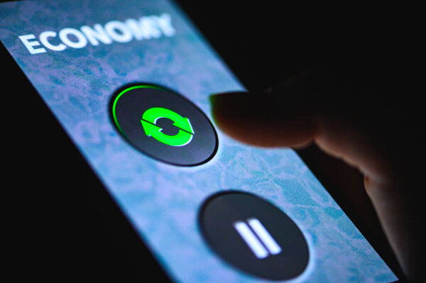 Economy Restart after coronavirus covid pandemic. Hand pressing the green restart button on display. The increase to the global economy from COVID-19. Time for restart