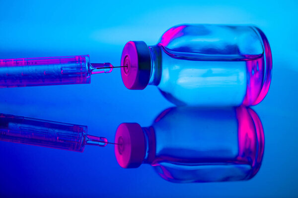 medical ampoules and syringe on blue background